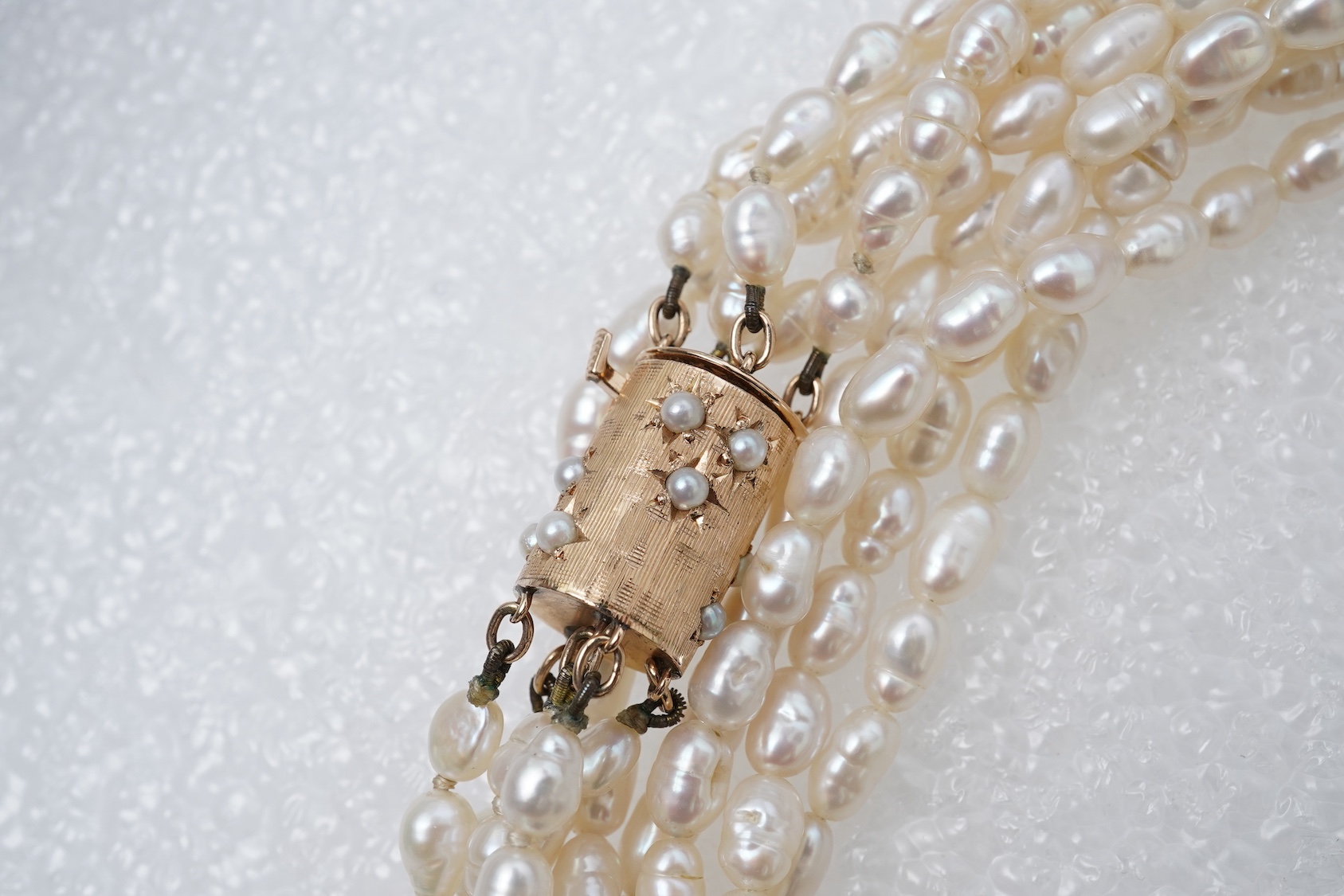 A cultured pearl and gold demi-parure, comprising a bracelet and necklace, each of torsade design, to gold barrel clasps with engraved details, set with split cultured pearls, bracelet length 19cm,necklace length 63cm, c